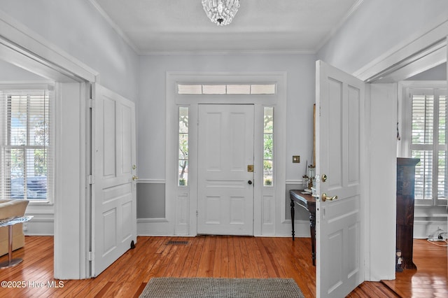 foyer entrance with wood-type flooring and ornamental molding