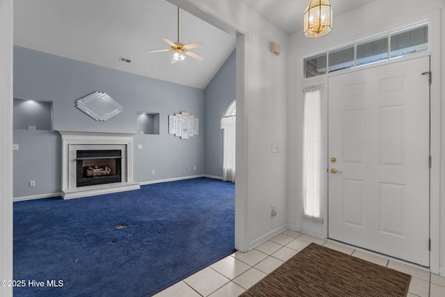 entrance foyer featuring tile patterned flooring, ceiling fan, a fireplace, baseboards, and high vaulted ceiling