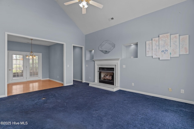 unfurnished living room with carpet, a fireplace with raised hearth, a chandelier, high vaulted ceiling, and baseboards