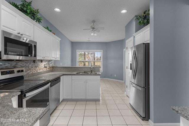 kitchen featuring appliances with stainless steel finishes, a sink, a ceiling fan, white cabinetry, and a textured ceiling