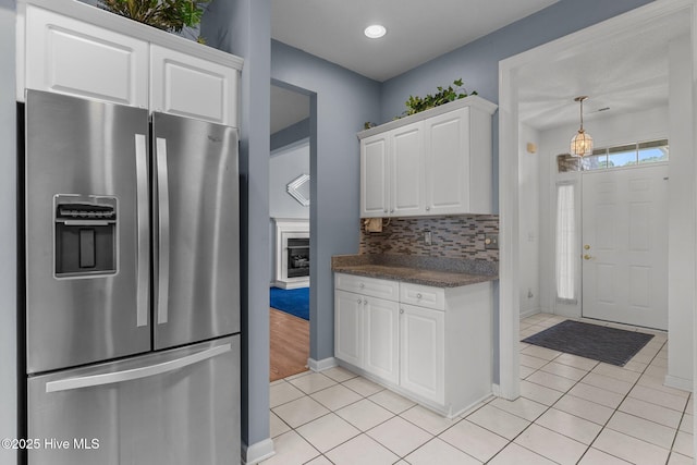 kitchen featuring stainless steel fridge, dark countertops, white cabinetry, light tile patterned floors, and recessed lighting
