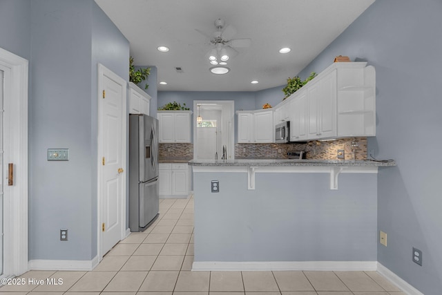 kitchen featuring appliances with stainless steel finishes, a peninsula, decorative backsplash, white cabinets, and recessed lighting