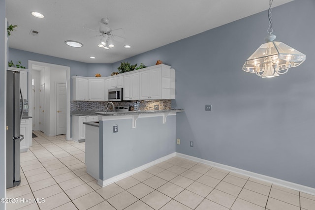 kitchen featuring a peninsula, appliances with stainless steel finishes, white cabinetry, light tile patterned flooring, and recessed lighting