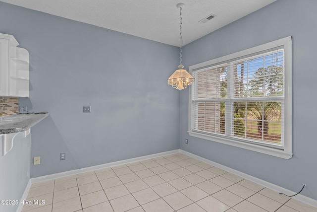 unfurnished dining area featuring a chandelier, baseboards, and light tile patterned flooring