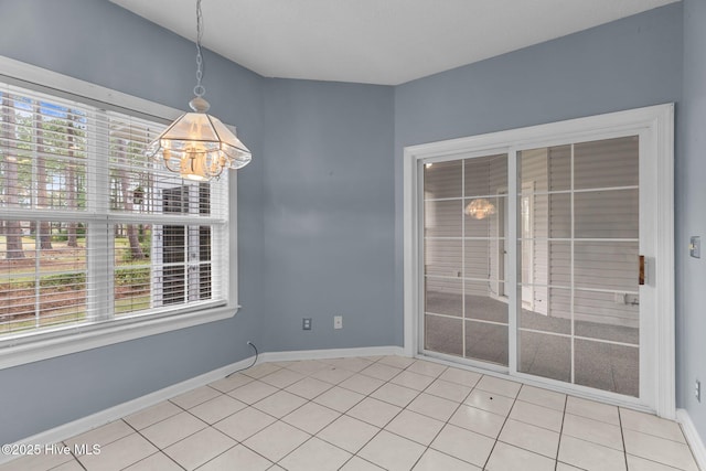 unfurnished dining area featuring a chandelier, baseboards, and light tile patterned floors
