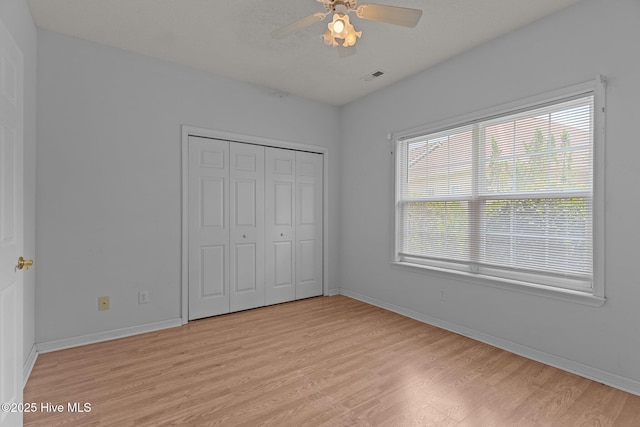 unfurnished bedroom with light wood-style flooring, baseboards, a closet, and a ceiling fan
