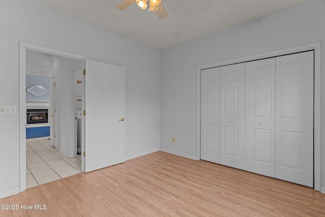 unfurnished bedroom with light wood-style floors, a closet, a ceiling fan, and baseboards