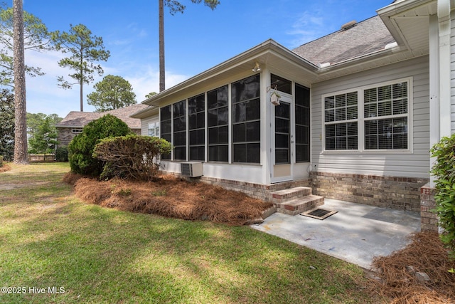 rear view of property featuring a sunroom, a yard, a patio area, roof with shingles, and entry steps