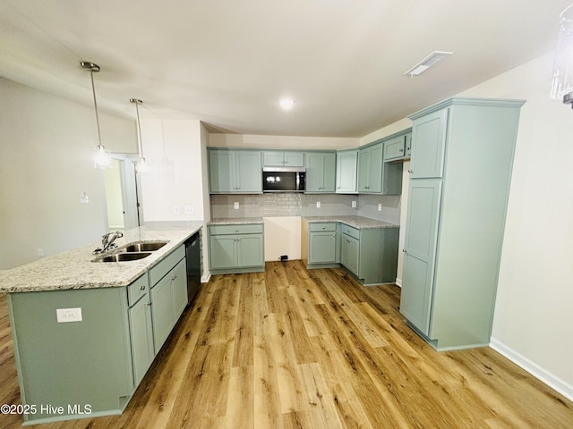 kitchen featuring a sink, stainless steel microwave, black dishwasher, a peninsula, and light wood-style floors