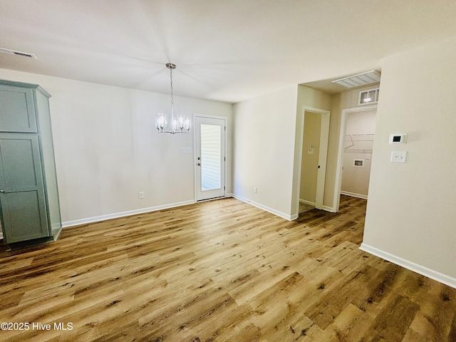 unfurnished dining area featuring wood finished floors, a chandelier, and baseboards