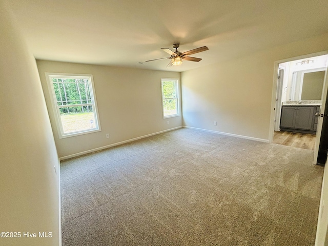 empty room featuring light carpet, ceiling fan, and baseboards
