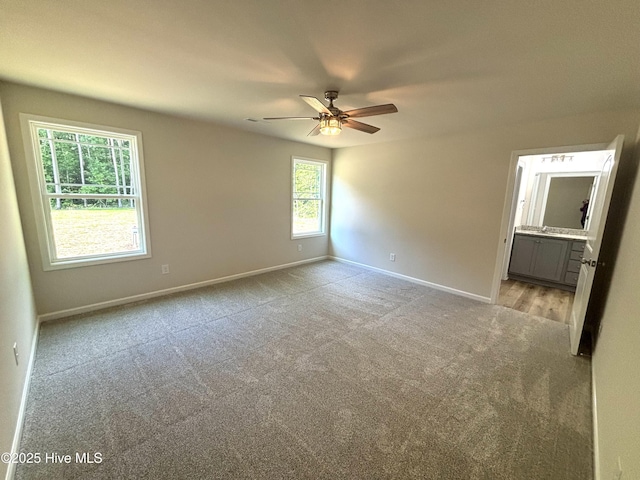 unfurnished bedroom with light colored carpet, baseboards, ensuite bathroom, and ceiling fan