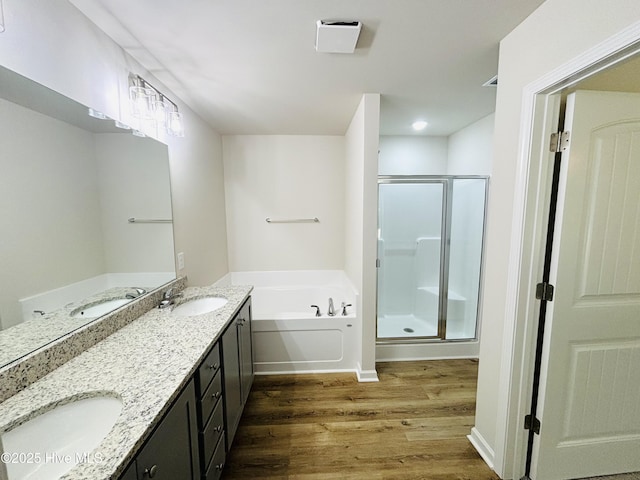 bathroom with wood finished floors, a garden tub, a shower stall, and double vanity