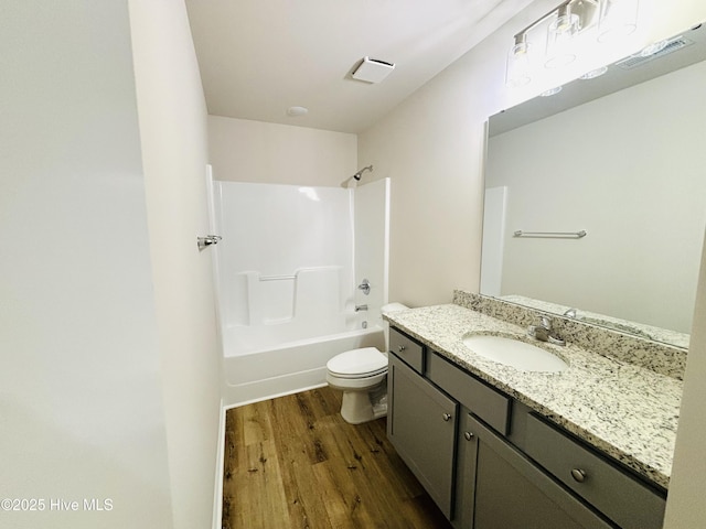 bathroom with wood finished floors, toilet, vanity, and  shower combination