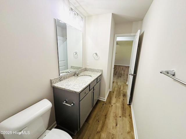 bathroom with wood finished floors, toilet, vanity, and baseboards