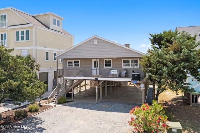 view of front of property featuring a carport, stairway, gravel driveway, central AC, and a porch