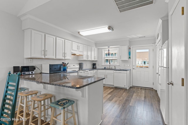 kitchen featuring white appliances, light wood-style floors, under cabinet range hood, a peninsula, and white cabinetry