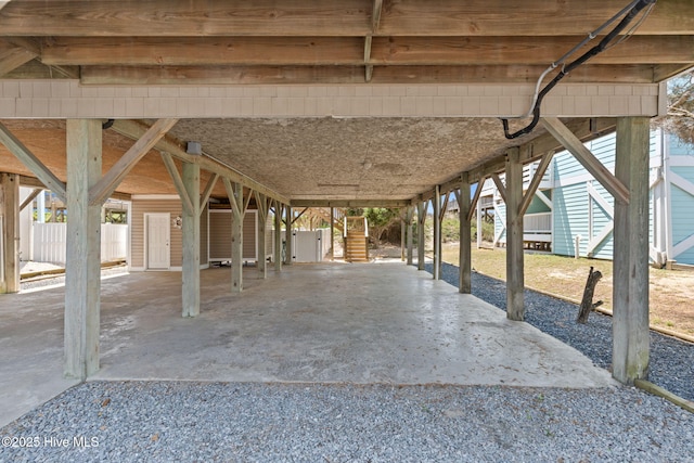 view of patio / terrace featuring a carport, stairway, fence, and gravel driveway
