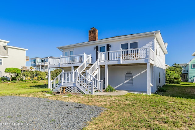 back of property featuring a chimney, a yard, and stairway