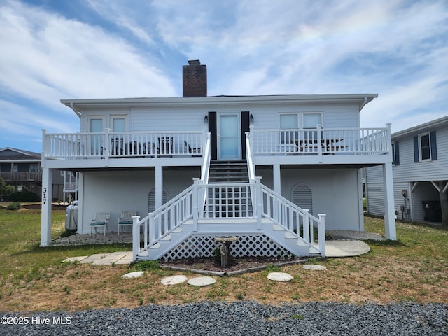 rear view of property featuring a chimney, stairway, and a wooden deck