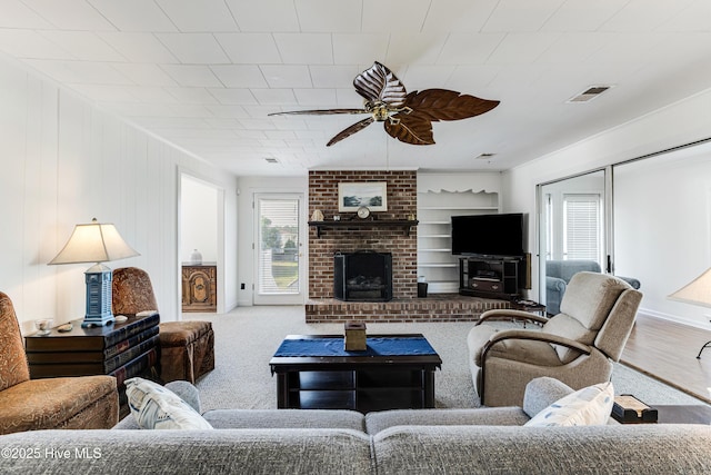 carpeted living room with ceiling fan and a fireplace