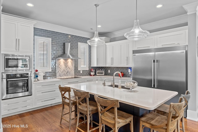 212 Cornubia Dr, Castle Hayne, NC 28429 - kitchen featuring built in appliances, wall chimney range hood, ornamental molding, tasteful backsplash, and a breakfast bar