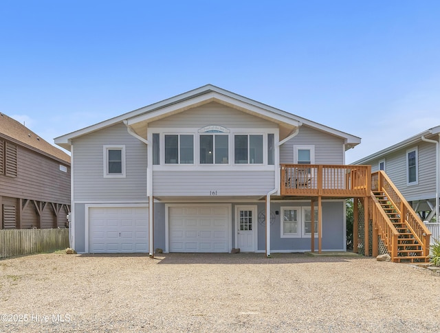 rear view of property with stairs, driveway, an attached garage, and a wooden deck