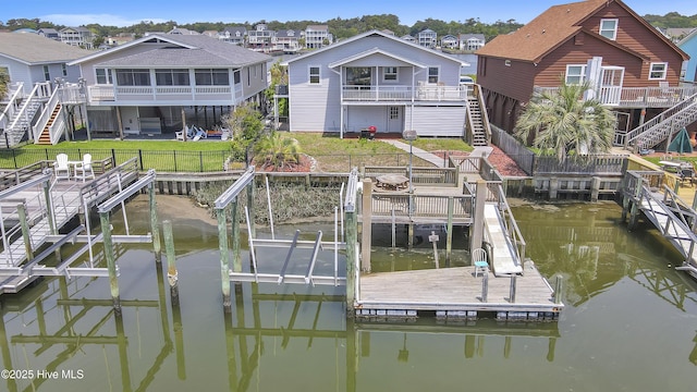 dock area featuring a fenced backyard, a water view, boat lift, and stairs
