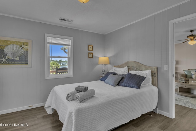bedroom with wood finished floors, baseboards, and ornamental molding
