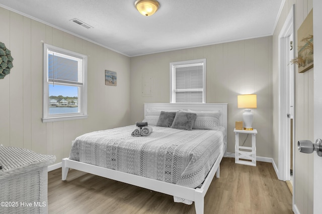 bedroom featuring ornamental molding, wood finished floors, baseboards, and a textured ceiling