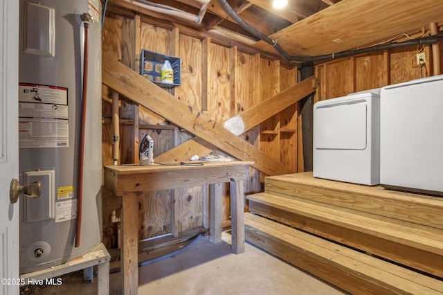 unfinished below grade area featuring water heater and separate washer and dryer