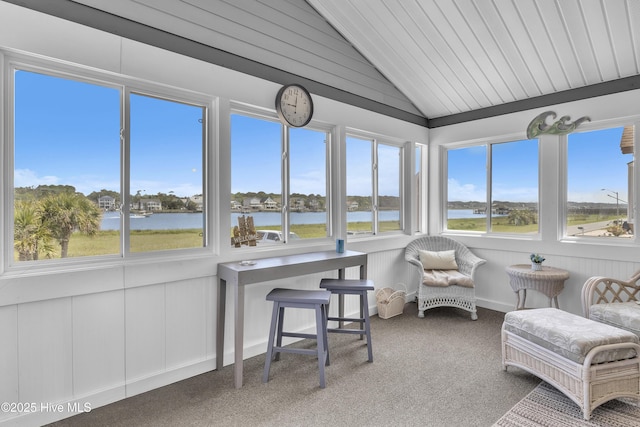 sunroom with lofted ceiling, healthy amount of natural light, carpet flooring, and a water view