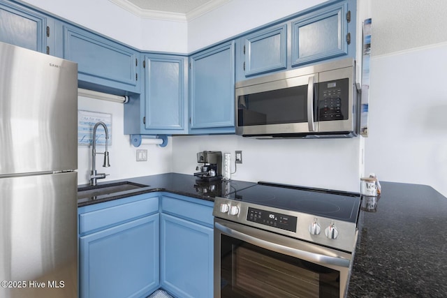 kitchen with appliances with stainless steel finishes, a sink, blue cabinetry, crown molding, and dark stone countertops