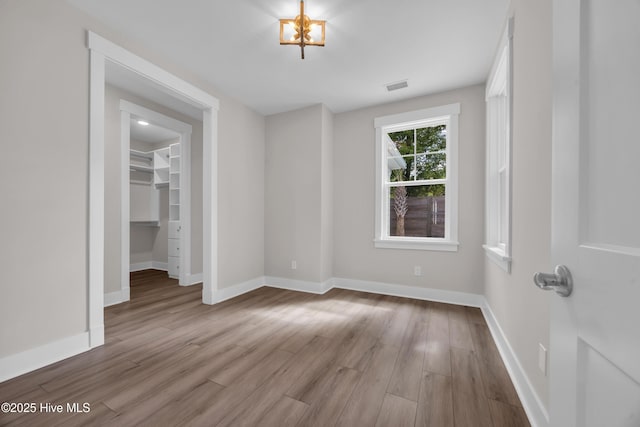 empty room with wood finished floors, baseboards, and a chandelier