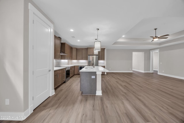 kitchen with stainless steel appliances, light countertops, baseboards, ceiling fan, and a raised ceiling