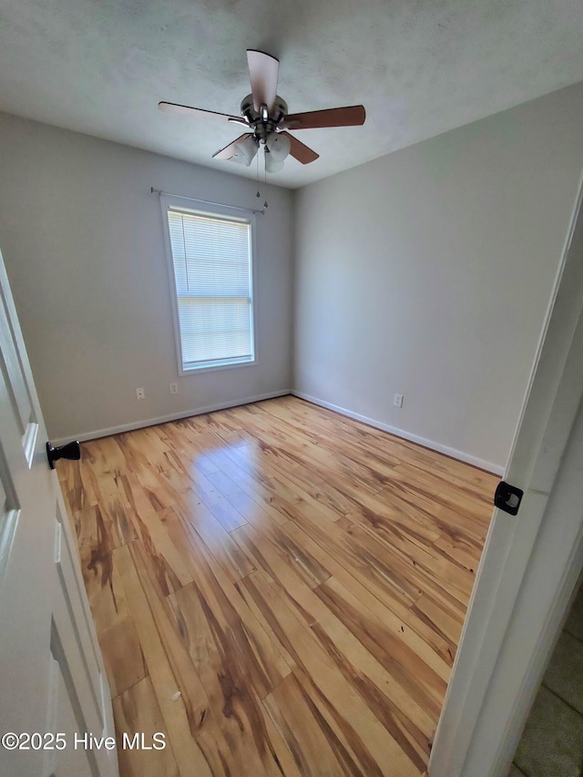 empty room with light wood-style floors, ceiling fan, and baseboards
