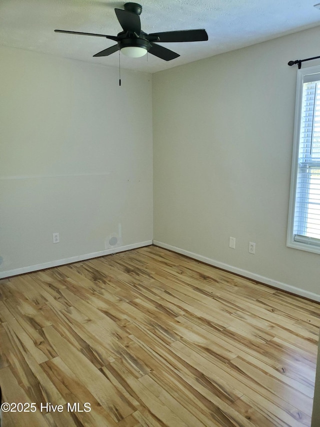 unfurnished room featuring light wood-type flooring, a ceiling fan, healthy amount of natural light, and baseboards