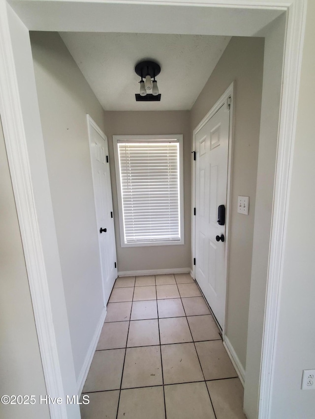 doorway to outside featuring baseboards and light tile patterned floors
