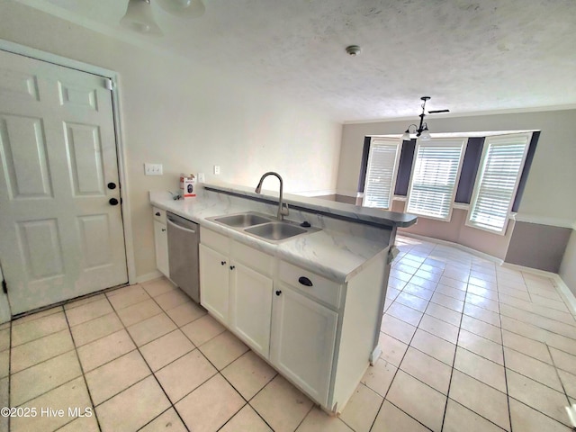 kitchen with a sink, stainless steel dishwasher, a peninsula, light tile patterned flooring, and white cabinetry