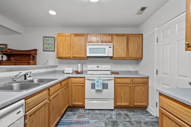 kitchen featuring white appliances, a sink, light countertops, and recessed lighting