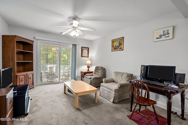 carpeted living room featuring ceiling fan and a desk