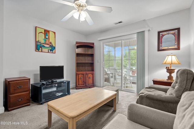 living room featuring light colored carpet, a ceiling fan, and baseboards