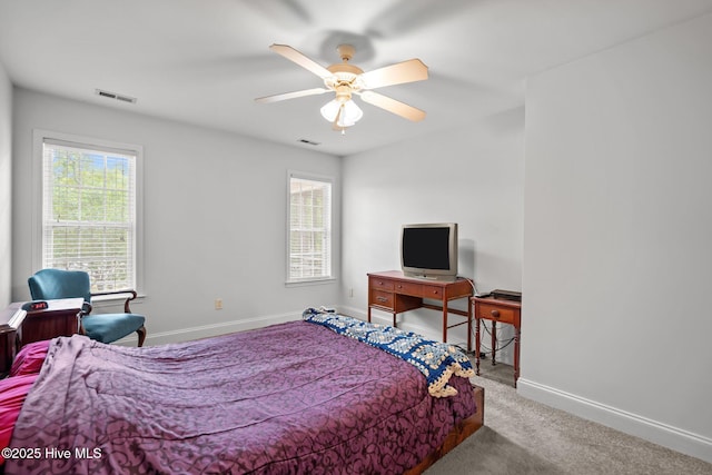 carpeted bedroom featuring multiple windows, baseboards, and a ceiling fan