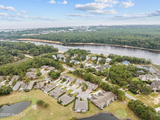aerial view of property's location featuring a large body of water, nearby suburban area, and a heavily wooded area