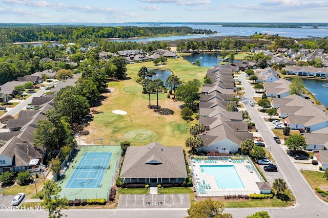 aerial view of residential area with a golf course, a nearby body of water, and a pool area