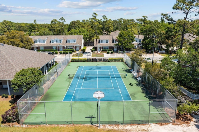 view of tennis court with fence and a residential view