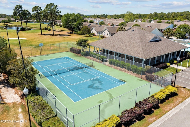 view of tennis court with fence and a residential view