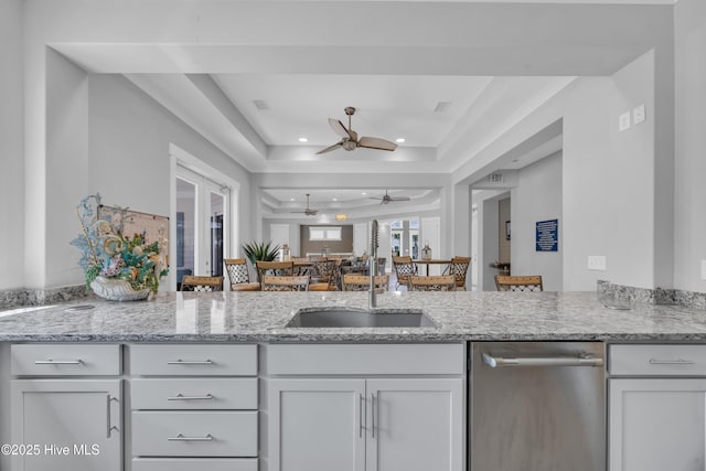 1961 Indigo Cove Way, Calabash, NC 28467 - kitchen with stainless steel dishwasher, a raised ceiling, ceiling fan, light stone counters, and recessed lighting