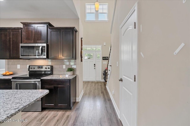 145 Cabin Branch Dr, Carthage, NC 28327 - kitchen featuring appliances with stainless steel finishes, light wood-style floors, dark brown cabinets, backsplash, and light stone countertops