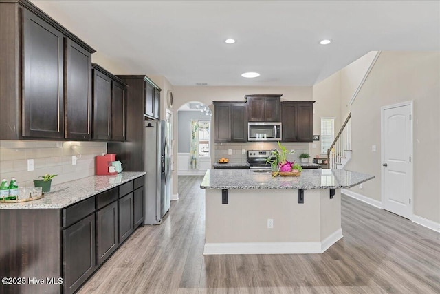 145 Cabin Branch Dr, Carthage, NC 28327 - kitchen featuring stainless steel appliances, arched walkways, decorative backsplash, light wood-type flooring, and dark brown cabinetry